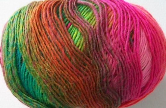 Buntes Wollknäul mit verlaufenden Farben in Pink, Grün und Orange.